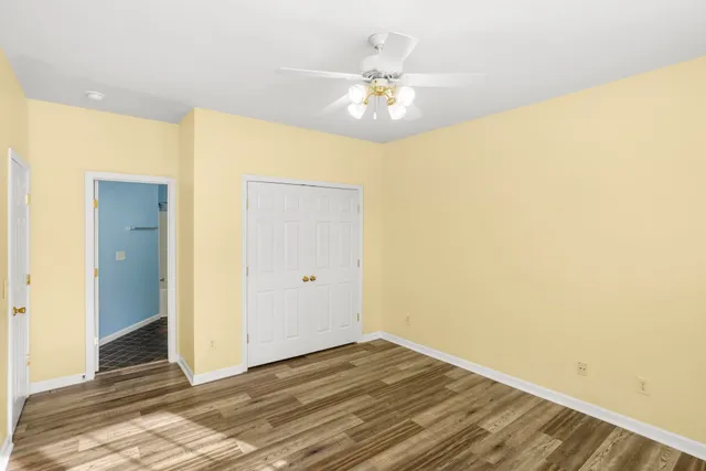 a view of an empty room with wooden floor and chandelier fan
