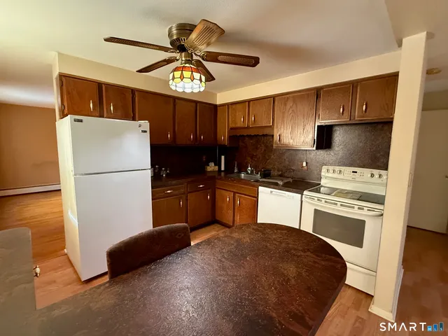 a kitchen with granite countertop a refrigerator a sink a stove and white cabinets