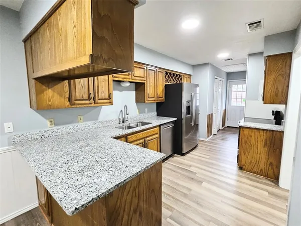 a kitchen with stainless steel appliances granite countertop wooden cabinets a granite counter top and a sink