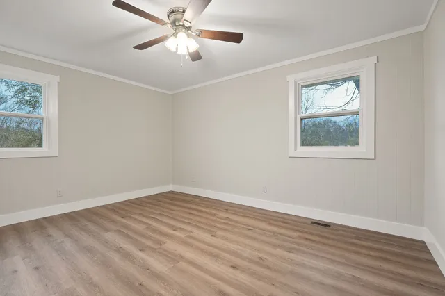 a view of an empty room with wooden floor and a window