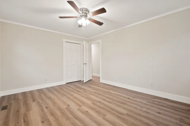 an empty room with wooden floor and a ceiling fan