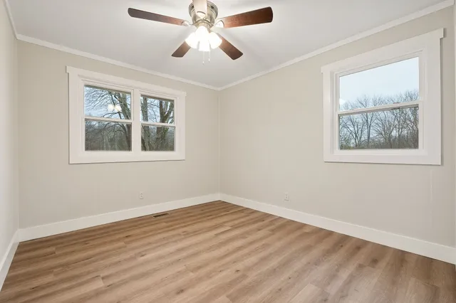 a view of an empty room with wooden floor and a window