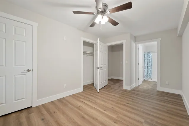 an empty room with wooden floor and ceiling fan