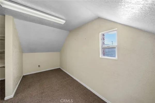 an empty room with wooden floor fireplace and windows