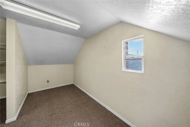an empty room with wooden floor fireplace and windows