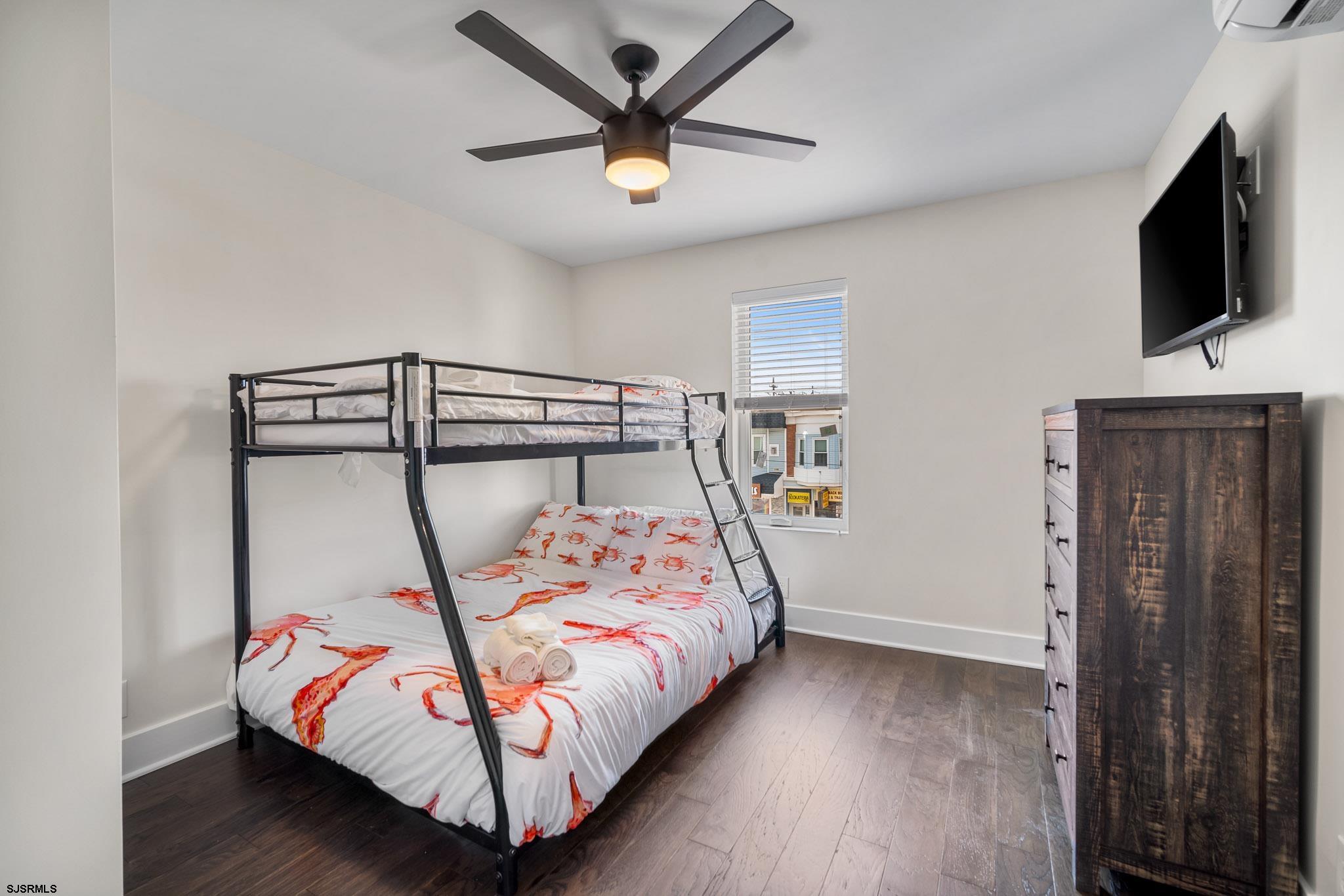 1059 Asbury Avenue, Unit 2 Ocean City, NJ 08226 - Photo 11 of 14 a bedroom with a bed and a flat tv screen on the dresser