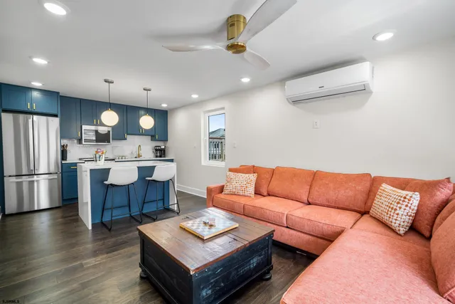 a living room with furniture a refrigerator and kitchen view