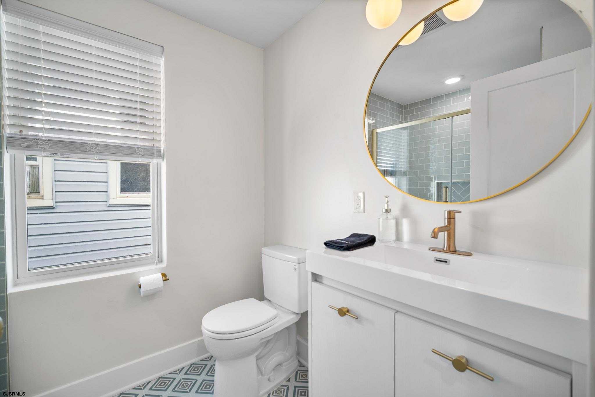 1059 Asbury Avenue, Unit 2 Ocean City, NJ 08226 - Photo 9 of 14 a bathroom with a sink a toilet and mirror