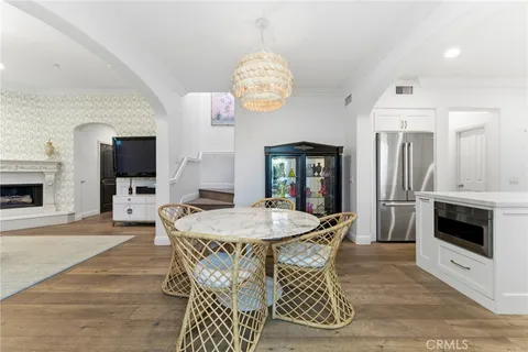 a dining room with wooden floor a chandelier a wooden table and chairs