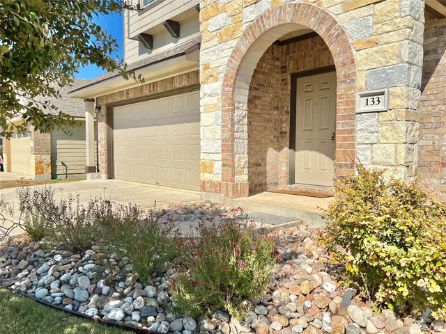 a view of a house with a small yard and large tree