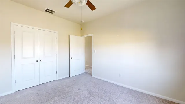 an empty room with ceiling fan and window