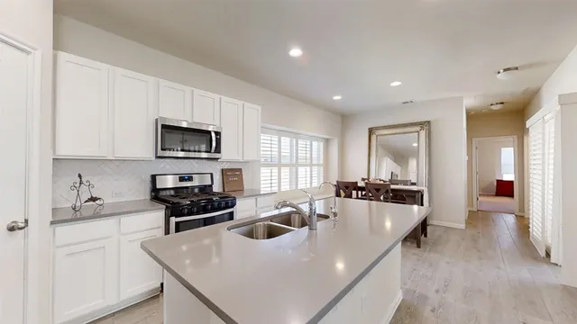 a large white kitchen with sink a refrigerator and cabinets