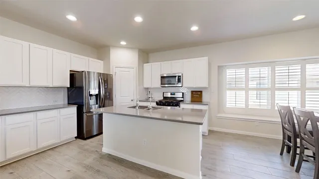 a kitchen with kitchen island white cabinets and stainless steel appliances