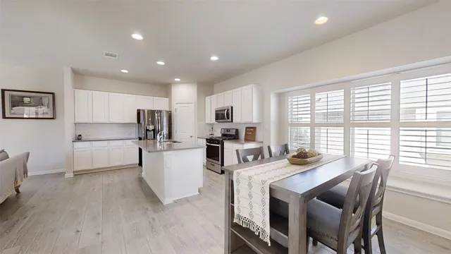 a kitchen with a table chairs microwave and cabinets