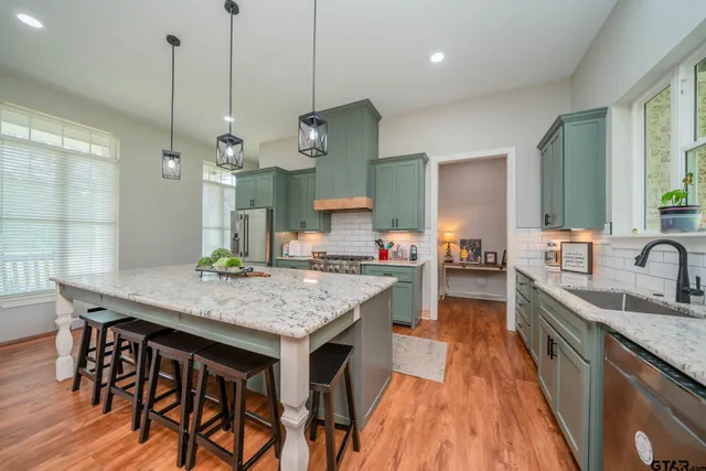a kitchen with a stove a sink a refrigerator and chairs
