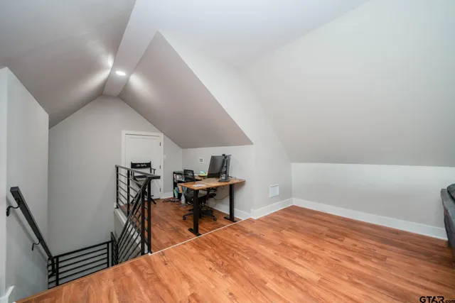 a view of an empty room with wooden floor and windows