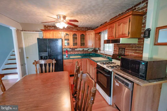 a kitchen with stainless steel appliances granite countertop a stove top oven a sink and a refrigerator