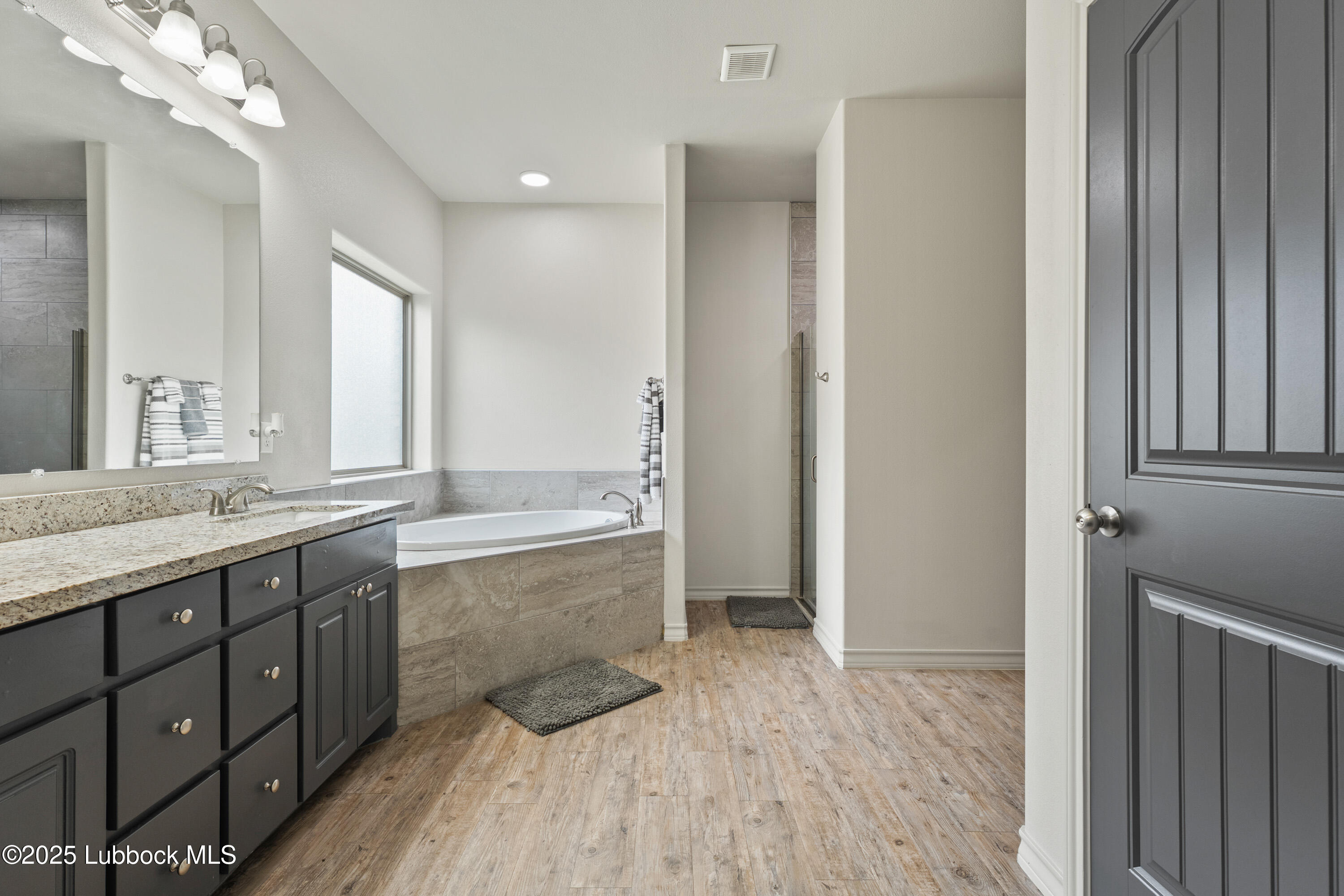 5303 Lehigh Street Lubbock, TX 79416 - Photo 16 of 31 a bathroom with a granite countertop double vanity sink a mirror and a bathtub