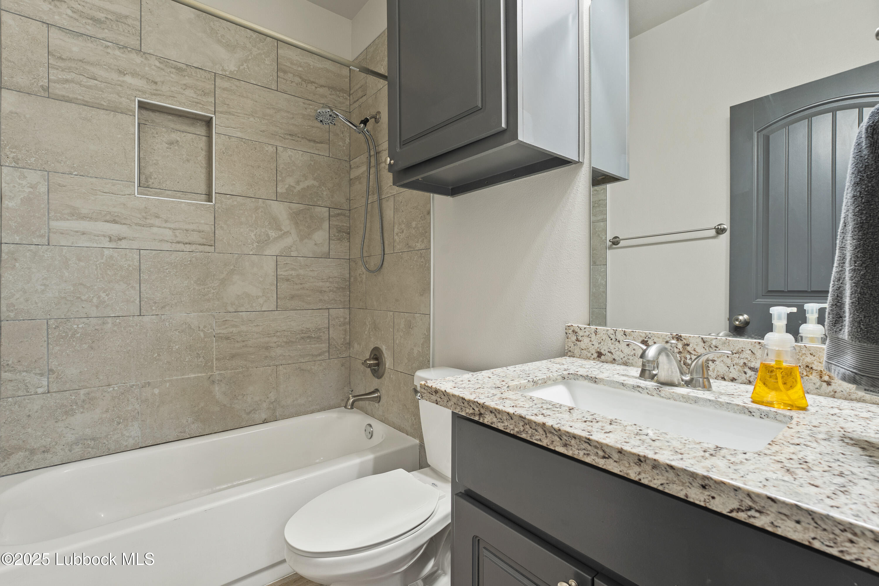 5303 Lehigh Street Lubbock, TX 79416 - Photo 24 of 31 a bathroom with a granite countertop sink a toilet and bathtub