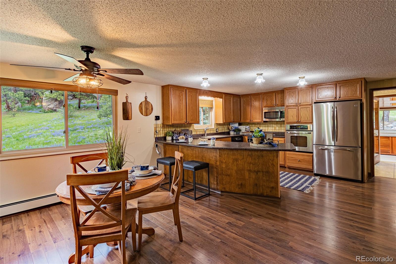 98 Button Rock Road Lyons, CO 80540 - Photo 4 of 40 a kitchen with stainless steel appliances granite countertop a refrigerator a stove a sink a dining table and chairs with wooden floor