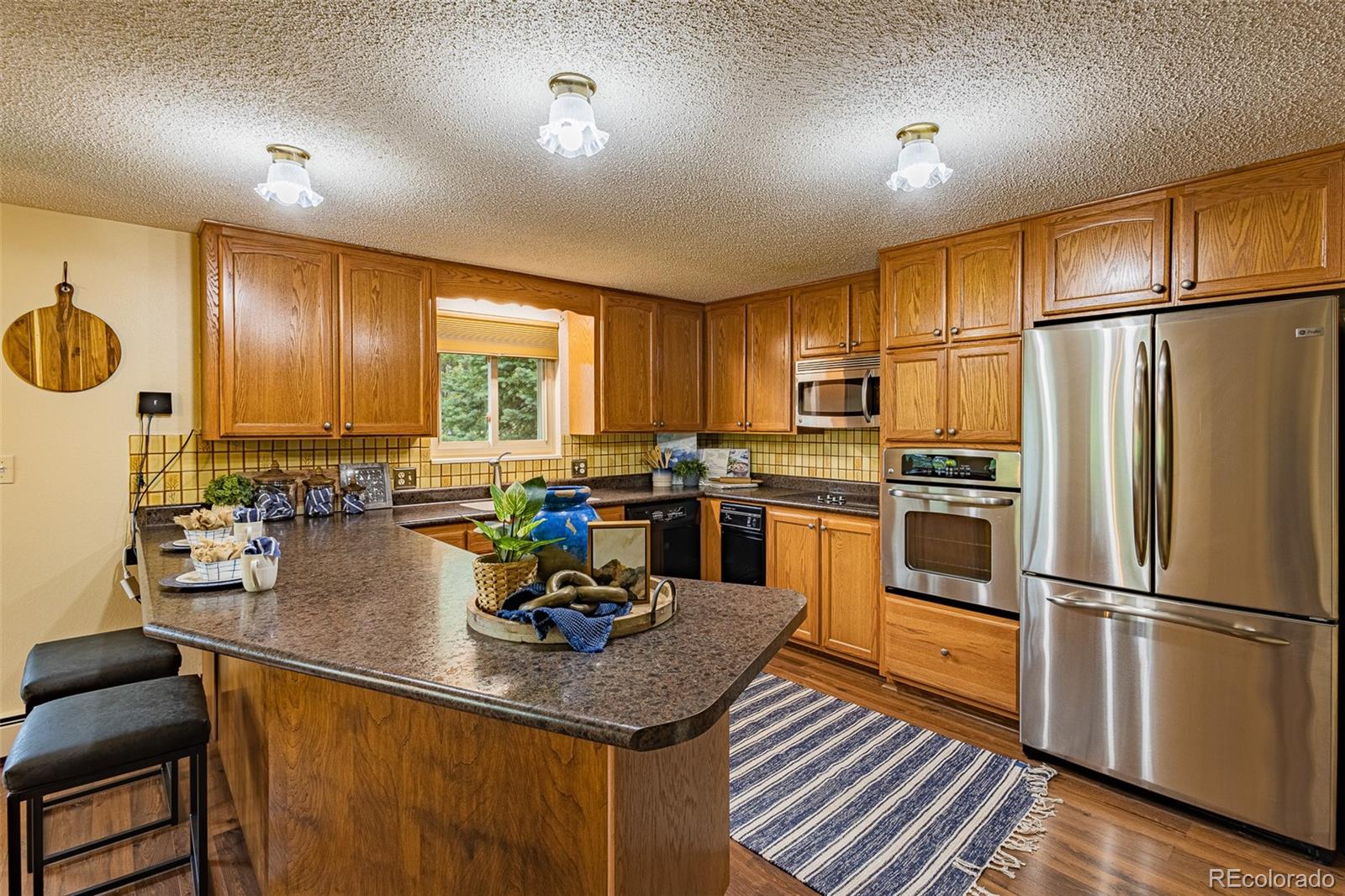 98 Button Rock Road Lyons, CO 80540 - Photo 6 of 40 a kitchen with refrigerator a stove a sink dishwasher and white cabinets with wooden floor