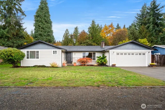 a view of a house with a yard and a large tree