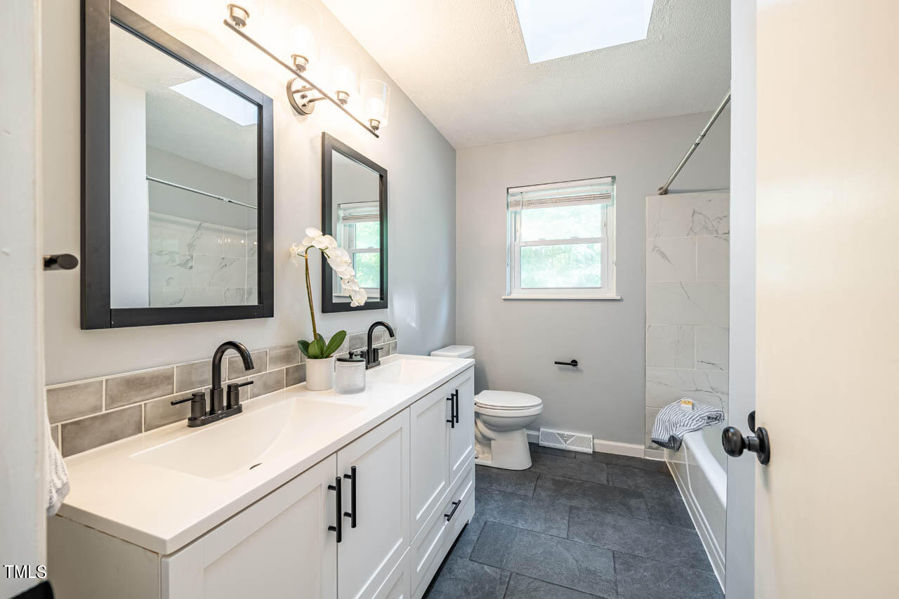210 Landsbury Drive Durham, NC 27707 - Photo 14 of 20 a bathroom with a double vanity sink toilet and mirror