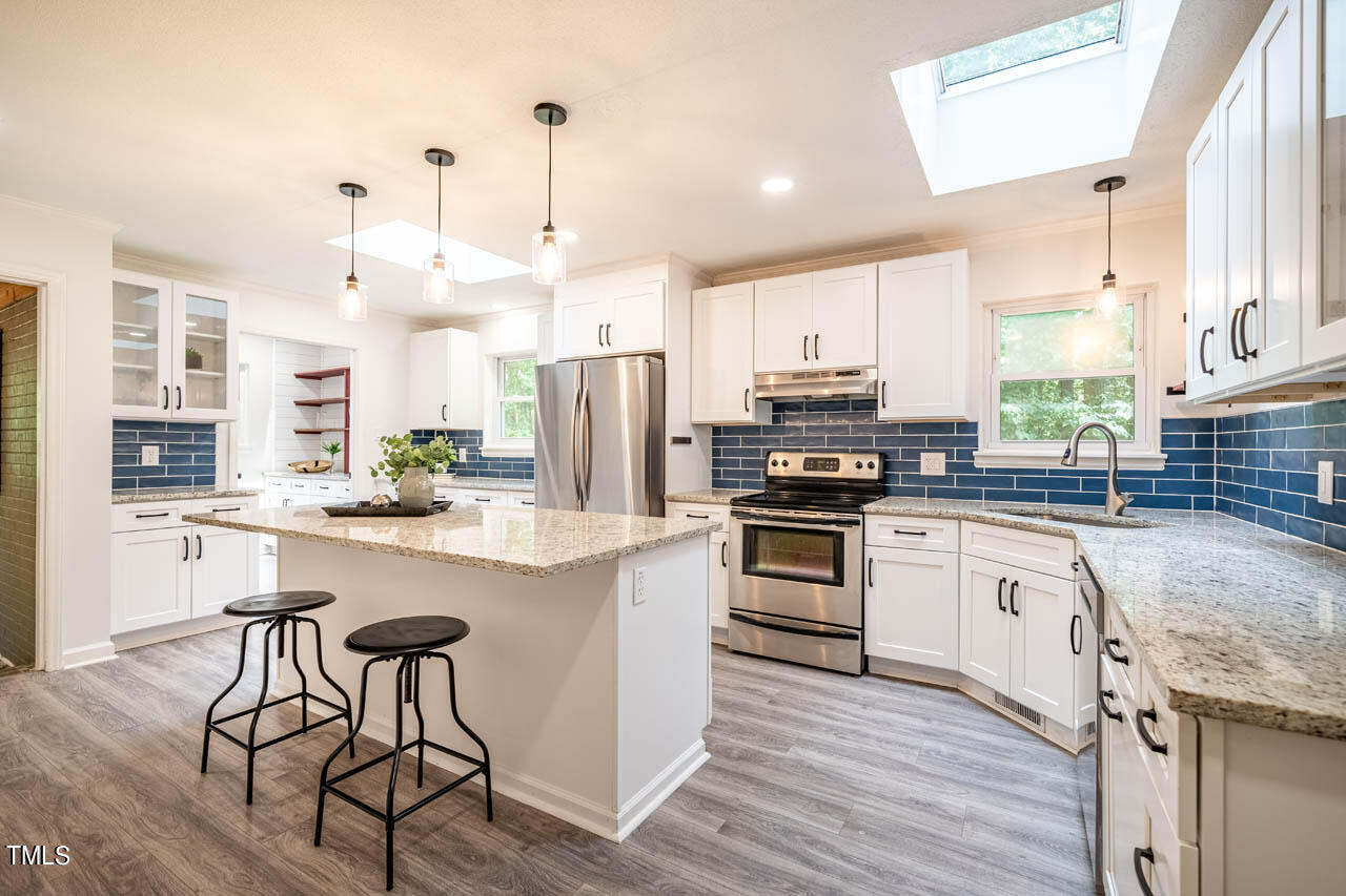 210 Landsbury Drive Durham, NC 27707 - Photo 4 of 20 a kitchen with stainless steel appliances granite countertop a stove refrigerator sink and cabinets