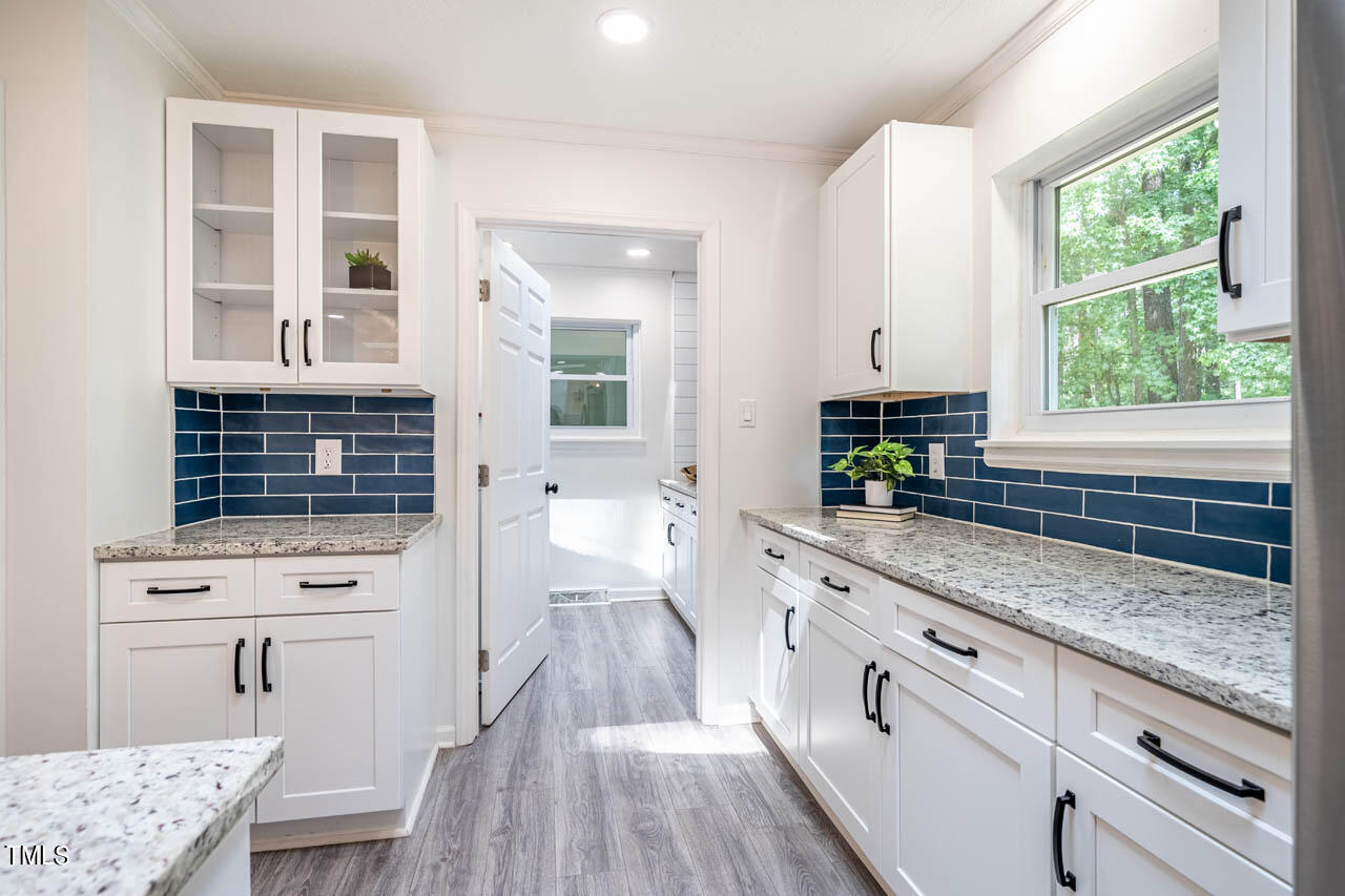 210 Landsbury Drive Durham, NC 27707 - Photo 6 of 20 a kitchen with granite countertop a stove a sink and white cabinets with wooden floor