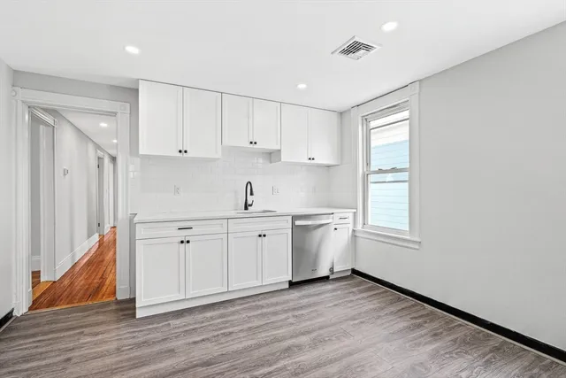 a view of a kitchen with a sink dishwasher and wooden floor