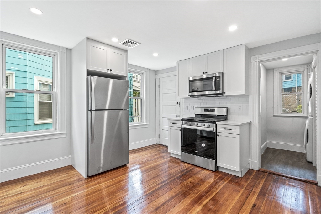 79 Pleasant Street Boston, MA 02125 - Photo 7 of 34 a kitchen with wooden floors and stainless steel appliances