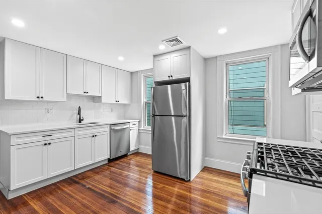 a kitchen with a refrigerator and white cabinets