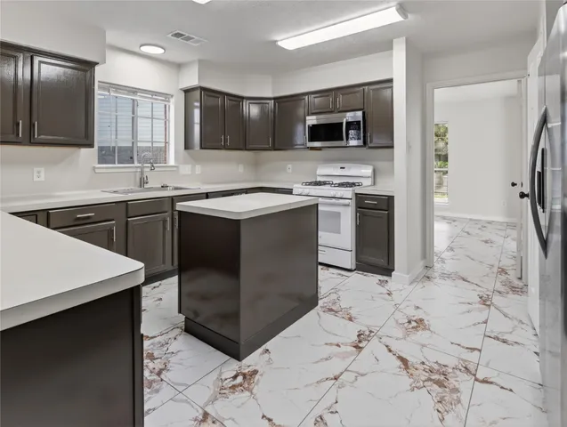 a kitchen with stainless steel appliances granite countertop a sink stove and refrigerator