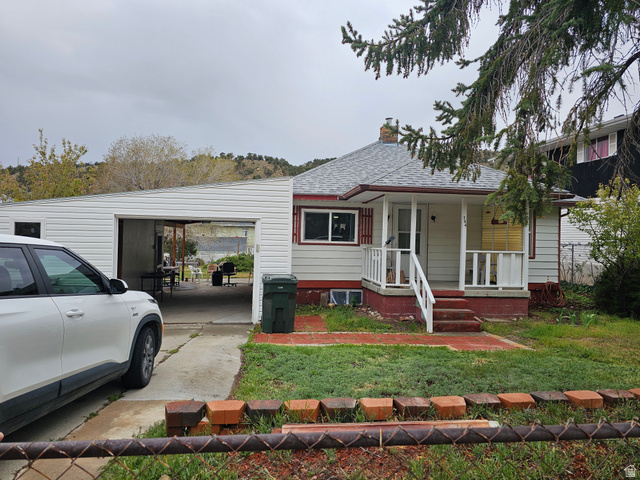 744 Royal Street Helper, UT 84526 - Photo 1 of 33 View of front of home featuring a chimney, covered porch, a shingled roof, an attached carport, and a front lawn