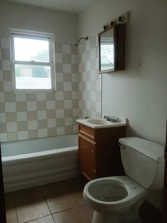 an empty room with chandelier fan and windows
