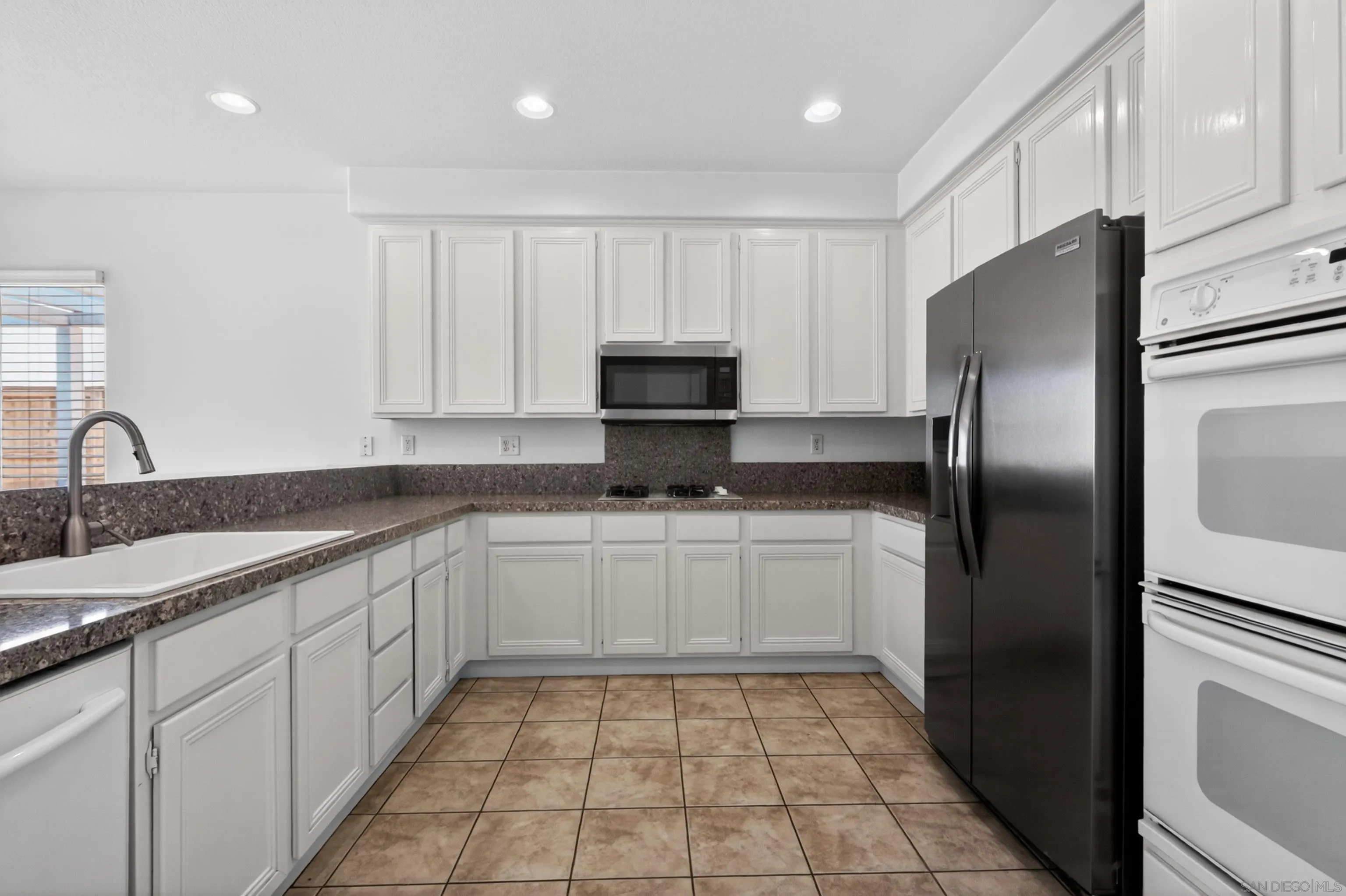 1432 Belmont Park Road Oceanside, CA 92057 - Photo 19 of 54 a kitchen with a sink a refrigerator and cabinets