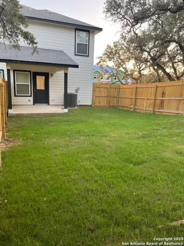 a view of backyard with wooden fence and large trees