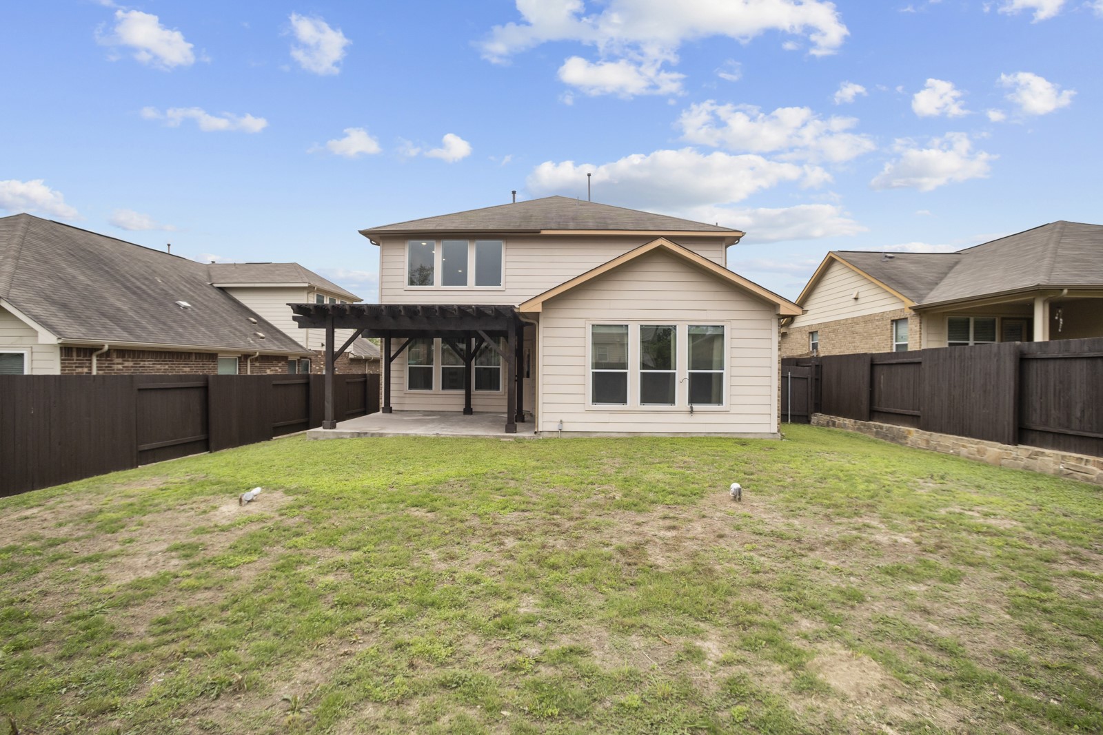245 Razzmatazz Trail Buda, TX 78610 - Photo 34 of 37 Expansive backyard featuring a pergola-covered patio with concrete flooring, a manicured lawn, and dark wood fencing