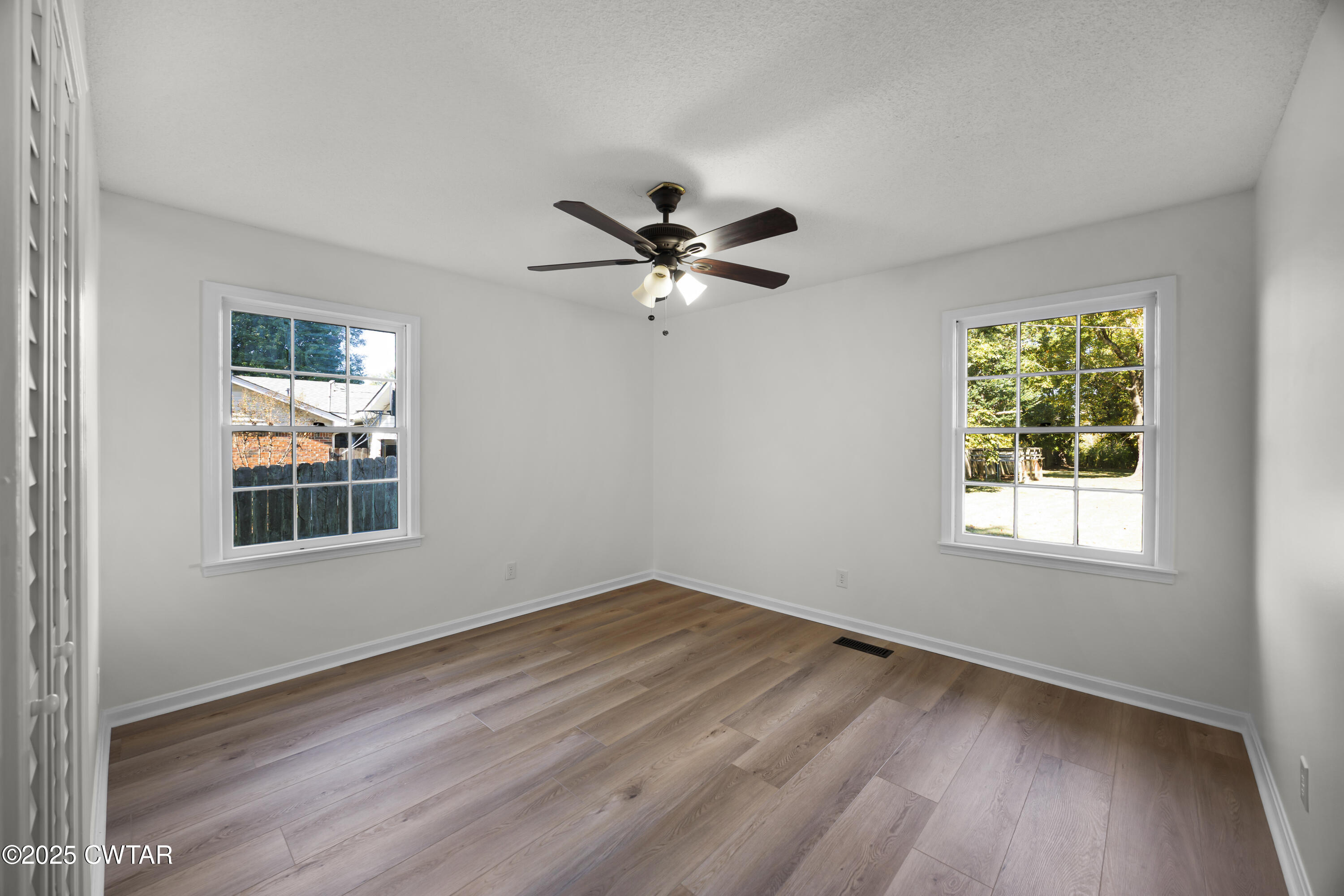 247 Highway 412 Jackson, TN 38305 - Photo 23 of 29 an empty room with wooden floor chandelier fan and windows