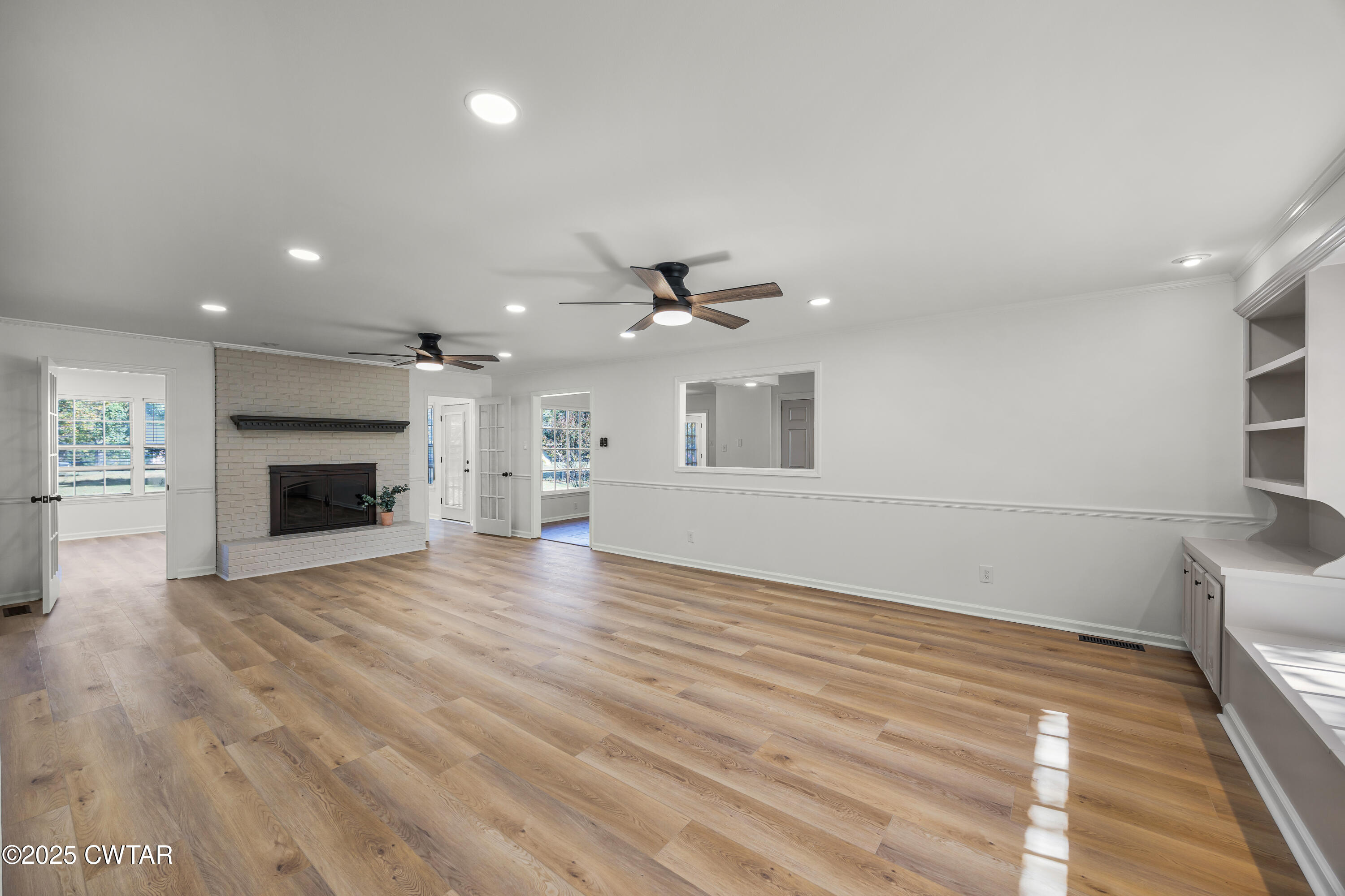 247 Highway 412 Jackson, TN 38305 - Photo 7 of 29 an empty room with wooden floor fireplace and windows