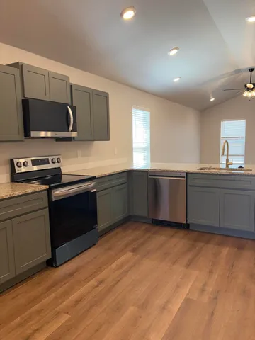 a kitchen with stainless steel appliances granite countertop a sink and a stove top oven