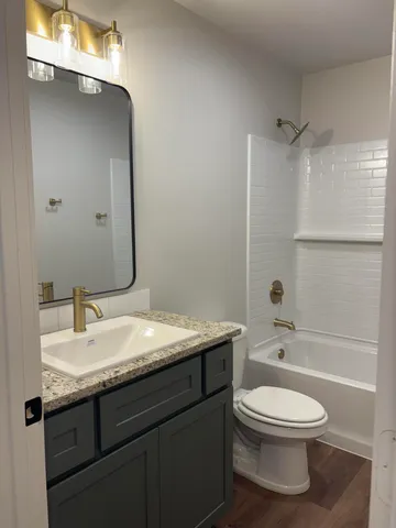 a bathroom with a granite countertop toilet a sink and a mirror
