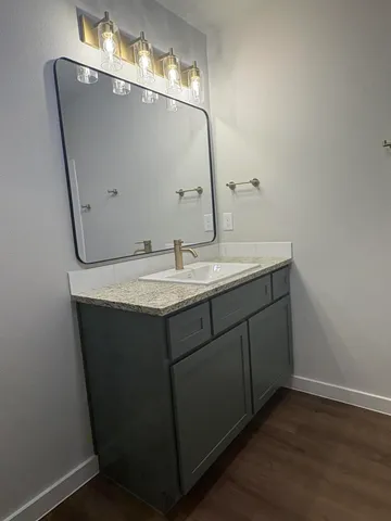 a bathroom with a granite countertop sink and a mirror