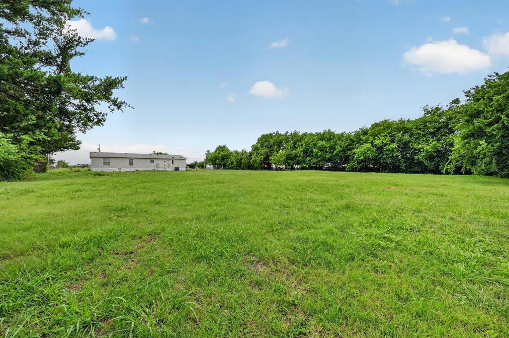13405 Wheat Road Venus, TX 76084 - Photo 31 of 32 Expansive green space featuring mature perimeter trees and a single-story structure with multiple window units