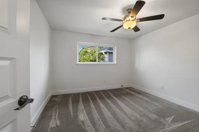 an empty room with ceiling fan and window