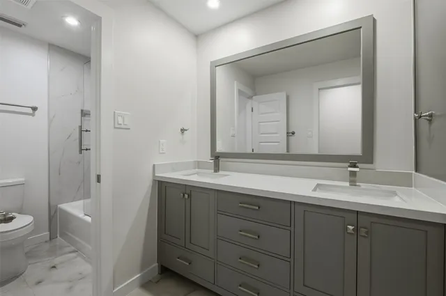 a bathroom with a double vanity sink toilet and shower