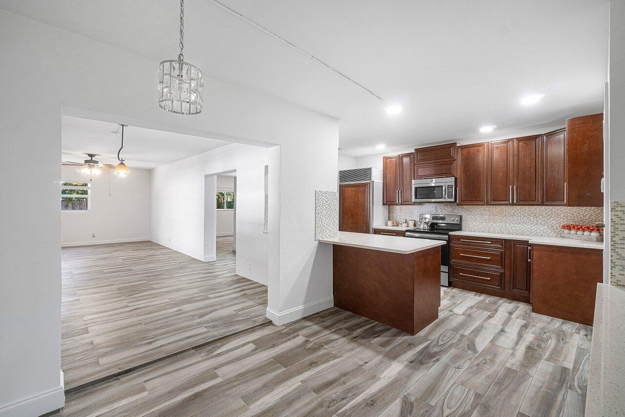 1641 Northwest 9th Street Boca Raton, FL 33486 - Photo 11 of 29 a large kitchen with kitchen island a sink a center island and stainless steel appliances