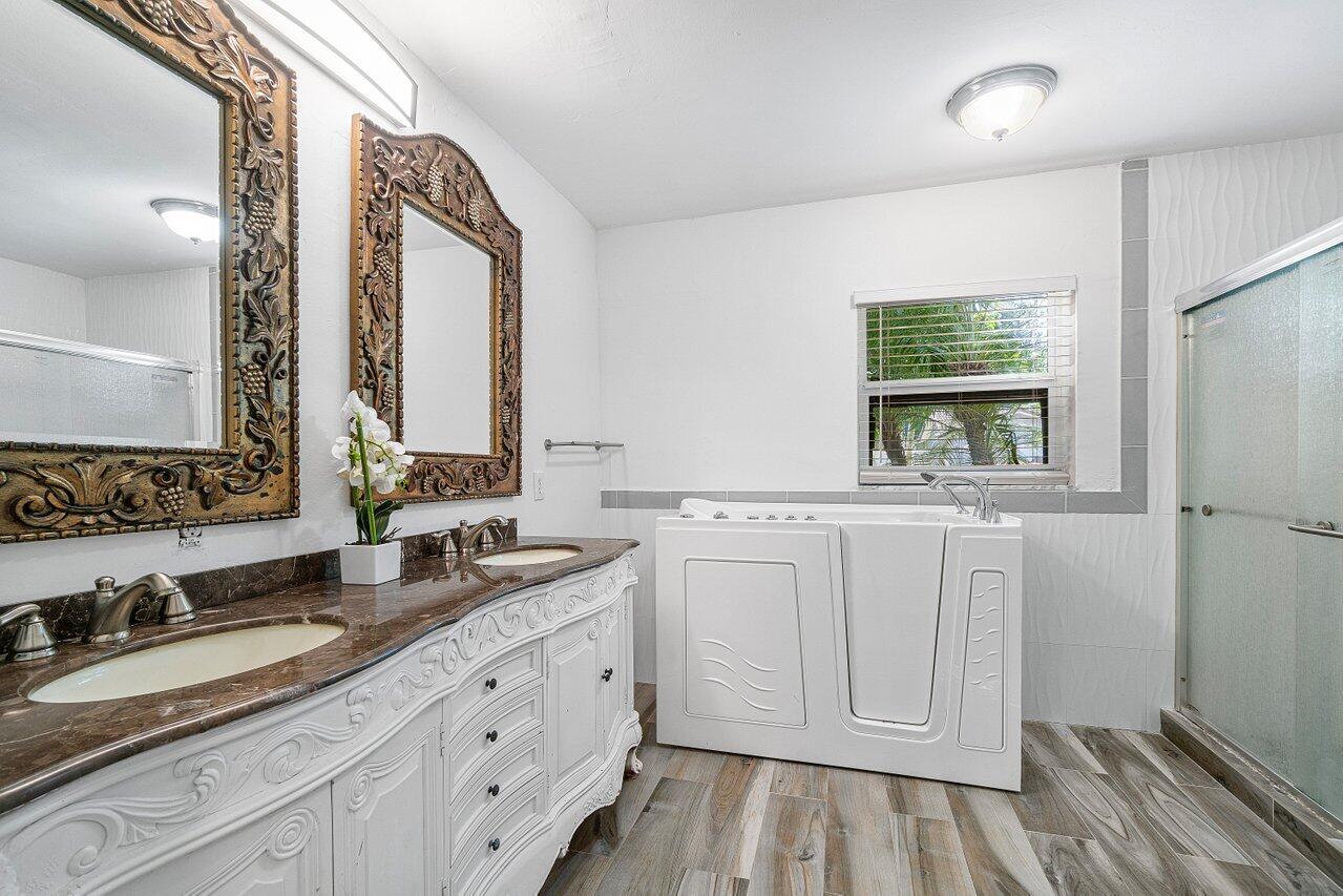 1641 Northwest 9th Street Boca Raton, FL 33486 - Photo 18 of 29 a bathroom with double vanity sink a mirror and a bathtub