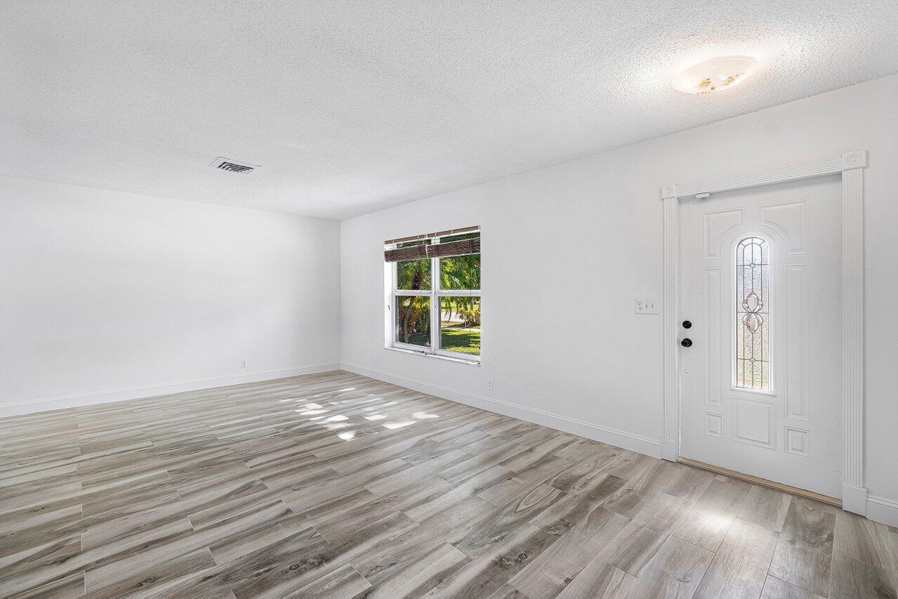 1641 Northwest 9th Street Boca Raton, FL 33486 - Photo 3 of 29 a view of an empty room with wooden floor and a window