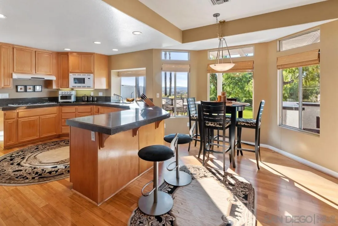 14268 Silver Ridge Road Poway, CA 92064 - Photo 19 of 53 a dining hall with stainless steel appliances granite countertop a stove top oven a dining table and chairs with wooden floor